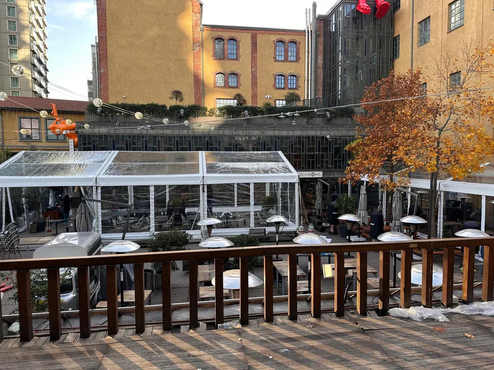 Restoran terasında camlı kapalı yemek alanı ve arkadaki tarihi tuğla cephe