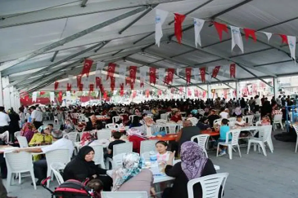 İftar çadırının içinde dolu sofralar ve bayraklı süslemeler