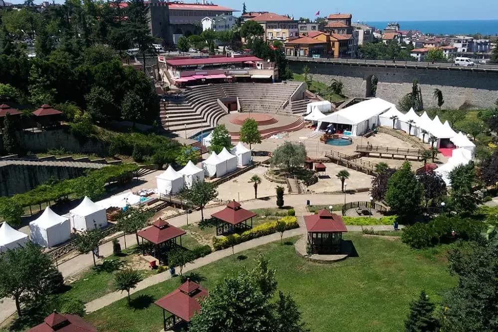 Havadan park alanı: sıralanmış beyaz kermes çadırları ve arkada deniz