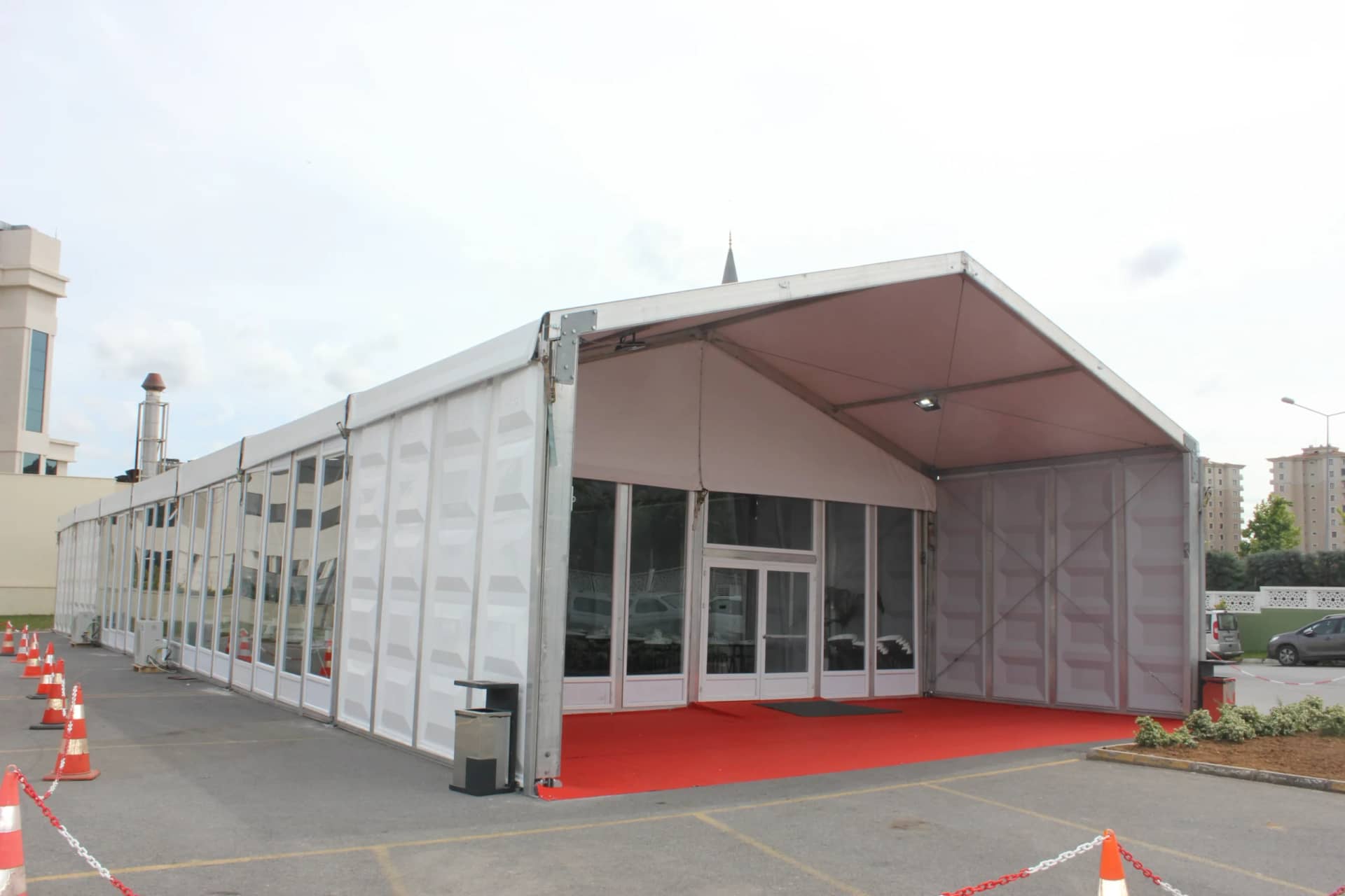 Otopark alanında kurulu, sert panel duvarlı ve camlı çift kapılı uzun yemekhane çadırı