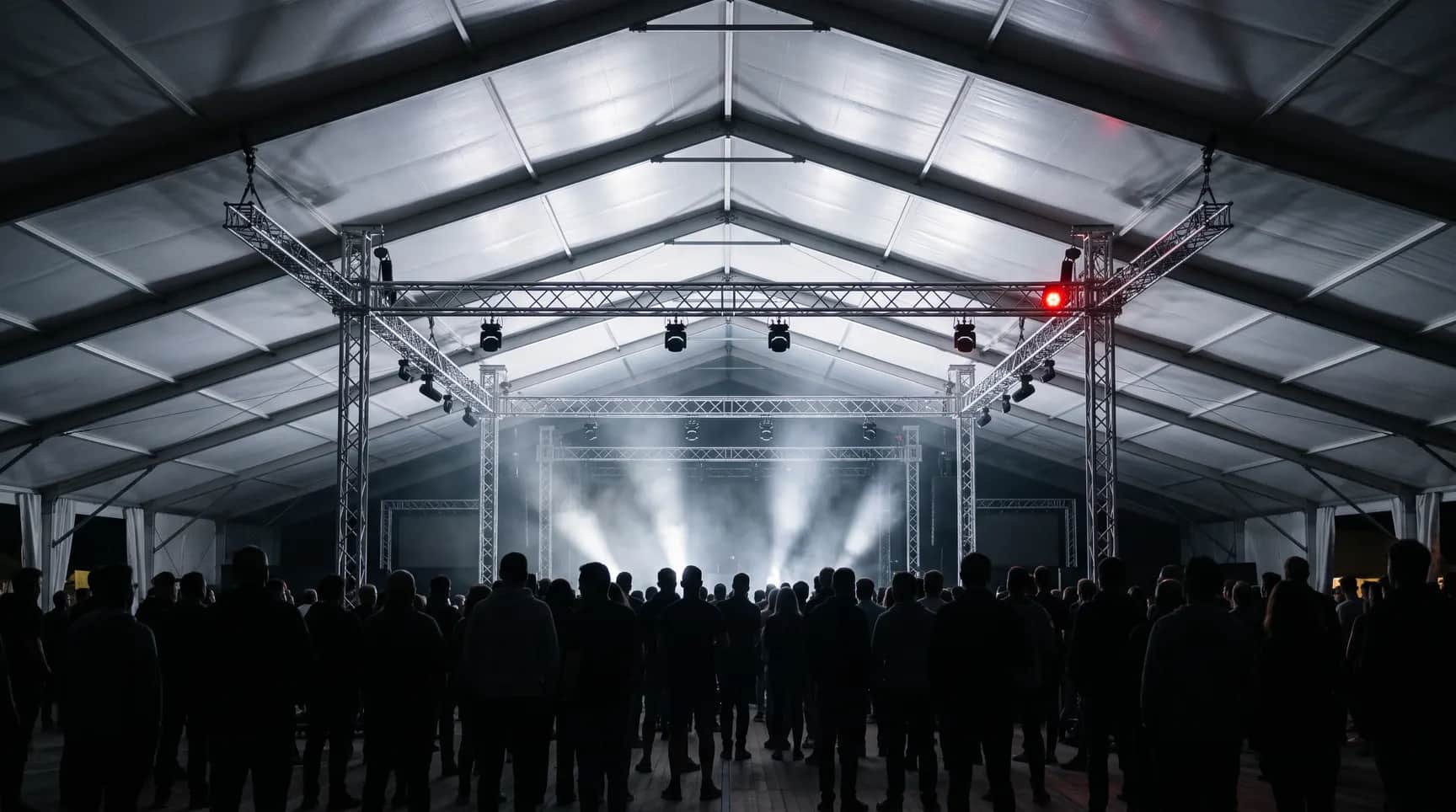 Gece festival çadırı: sahne trussları, ışık demetleri ve seyirci siluetleri