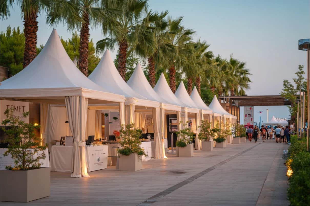 Antalya'da palmiyeli promenad boyunca sıralanmış beyaz pagoda stand çadırları
