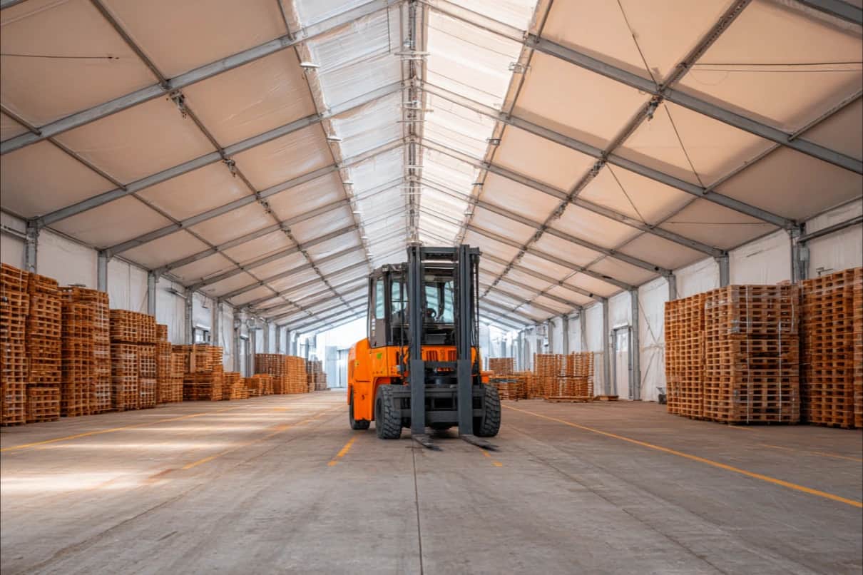 Depo çadırının içinde forklift ve iki yana istiflenmiş ahşap paletler