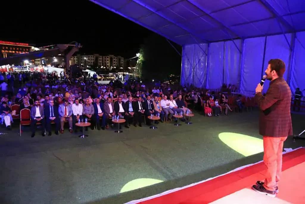 Gece ramazan etkinliğinde sahnedeki konuşmacı ve oturan kalabalık