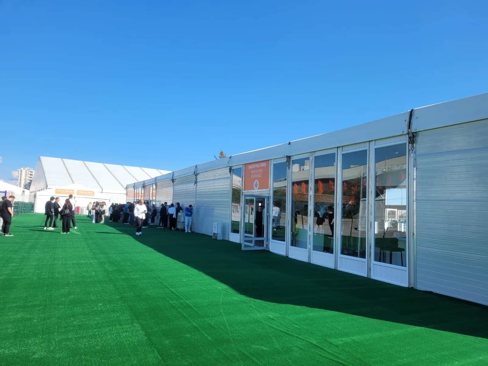 19. Growtech'te cam kapılı çadır cephesi ve suni çim kaplı ziyaretçi yolu