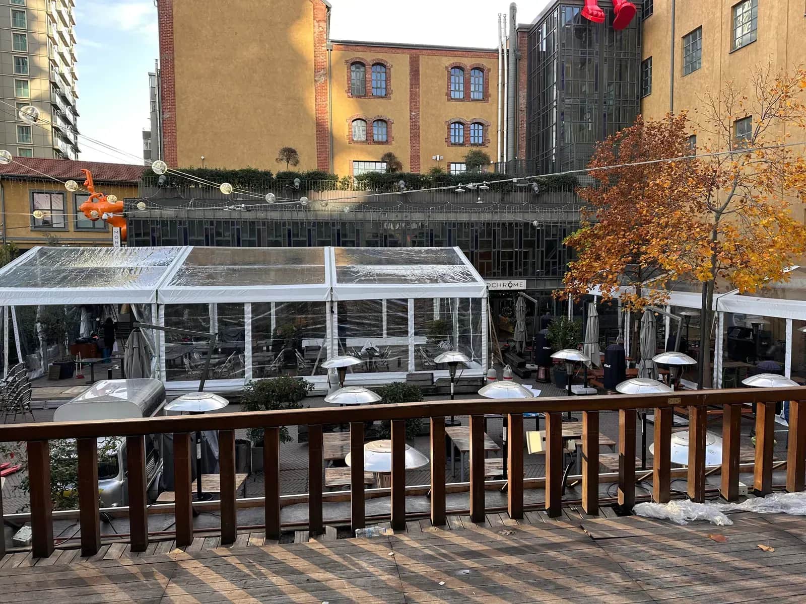 Restoran terasında camlı kapalı yemek alanı ve arkadaki tarihi tuğla cephe