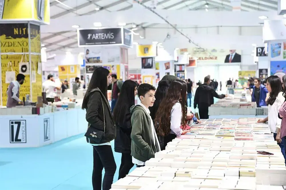 Kitap fuarı çadırında sergi standları ve kitap bakan ziyaretçiler