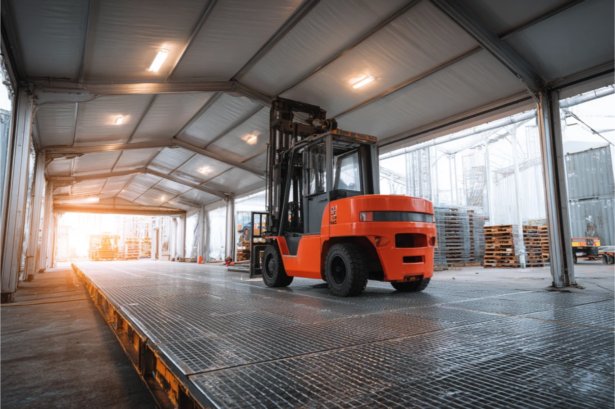 Endüstriyel çadır içinde ağır hizmet çelik ızgara podyum ve üzerinde turuncu forklift