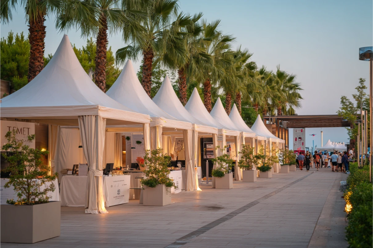 Antalya'da palmiyeli promenad boyunca sıralanmış beyaz pagoda stand çadırları