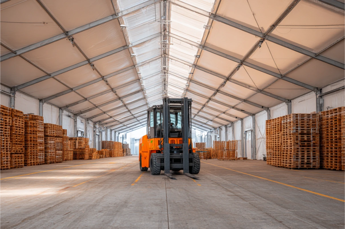 Depo çadırının içinde forklift ve iki yana istiflenmiş ahşap paletler