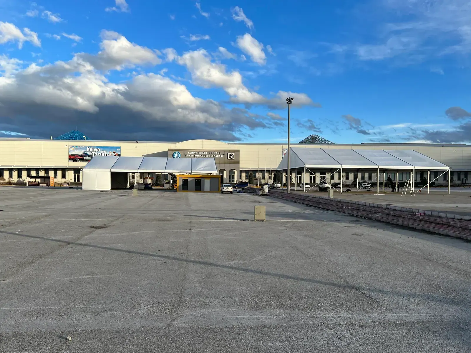 Fuar alanında uzun beyaz çadır ve önündeki otopark